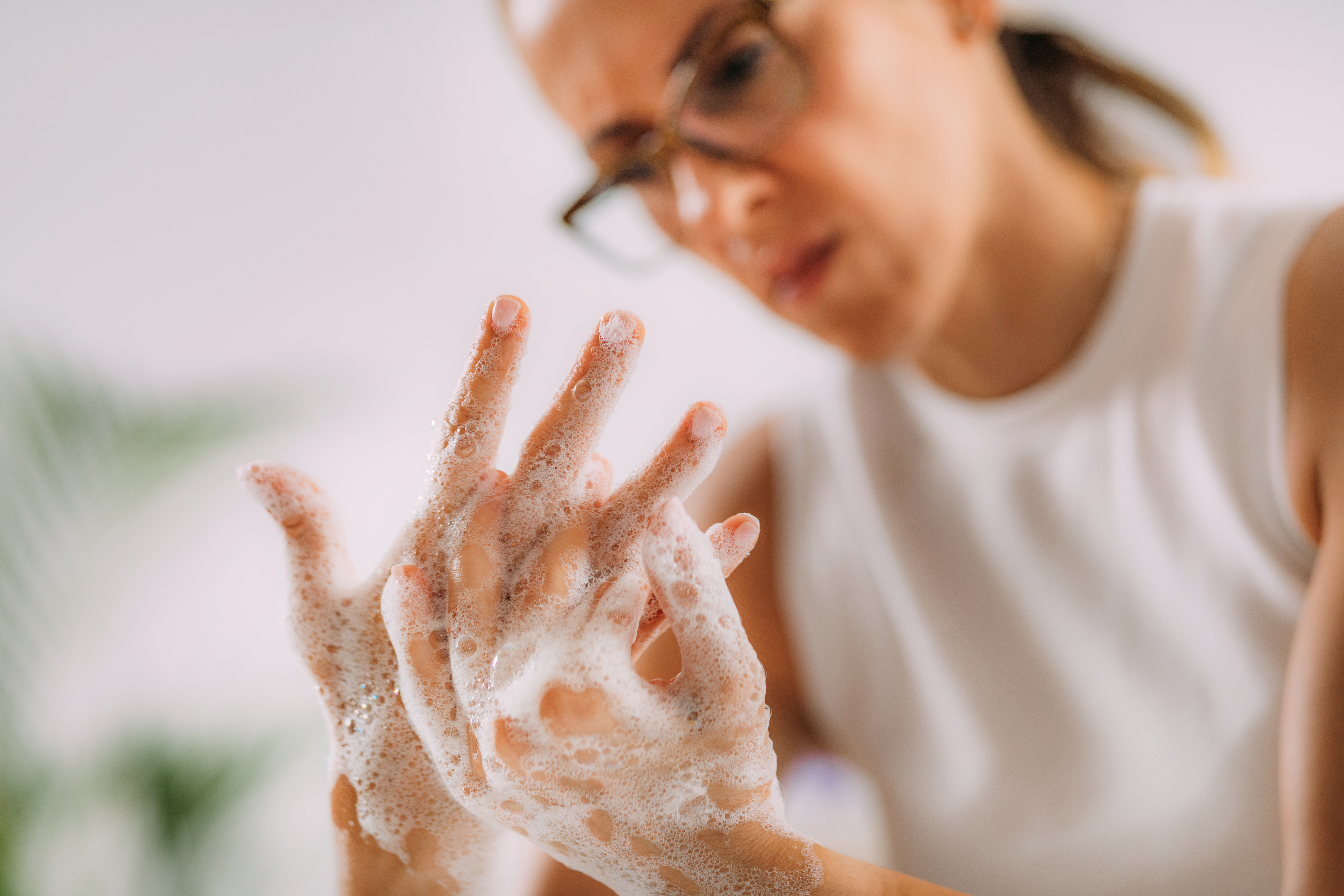 A woman is seen scrubbing her hands that are covered in sudsy soap. Excessive handwashing can be a sign of OCD.